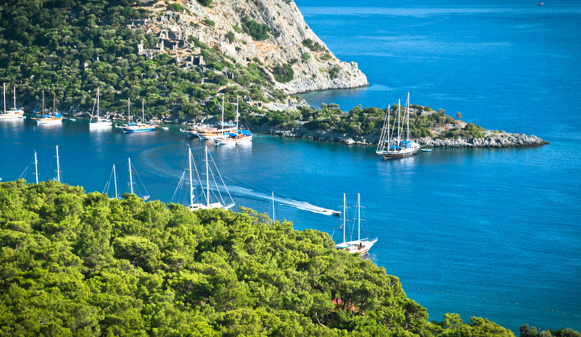 Yachts anchored in a forested island bay